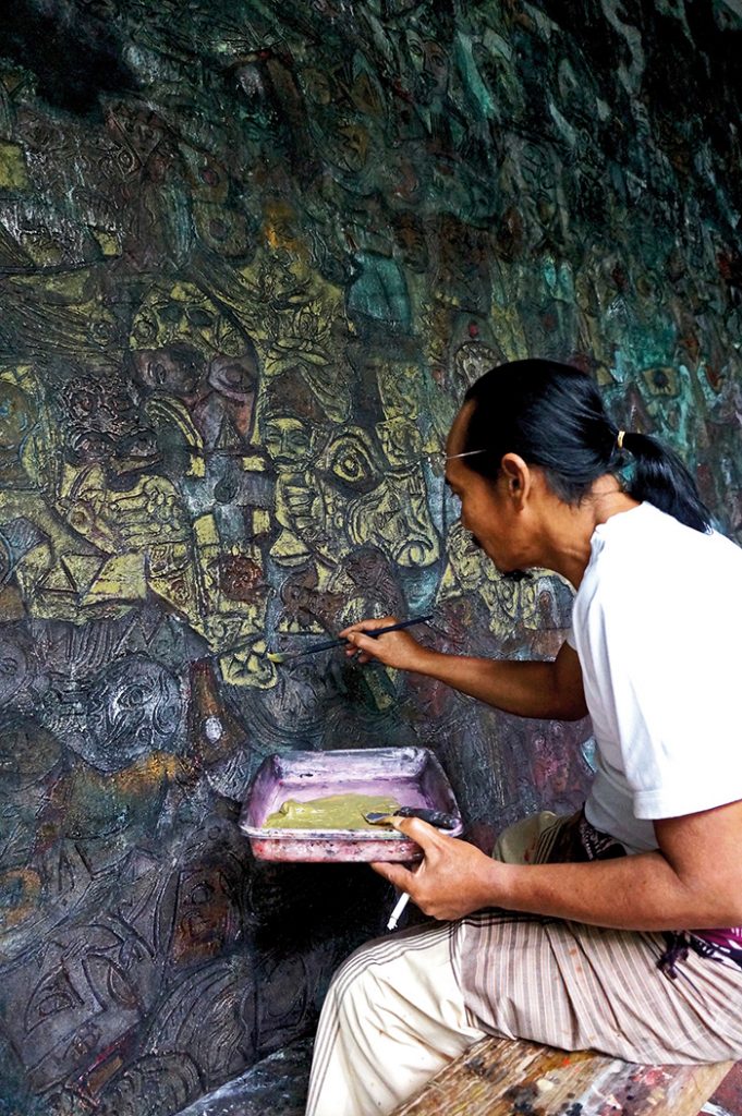 Celebrated Balinese painter I Made Djirna working in his home studio